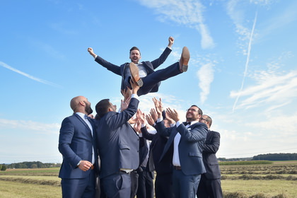 Trauzeugen werfen den Bräutigam übermütig in die Luft