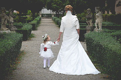 Braut mit Blumenmädchen Hand in Hand im Schlossgarten