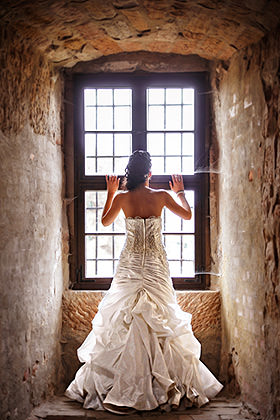 Braut am Burgfenster mit langem Kleid im warmen Licht