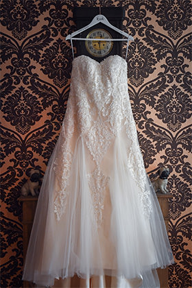 Brautkleid hängt vor einer barocken Tapete (Getting Ready)