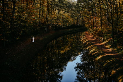 Braut am herbstlichen Flussufer, weite Waldstimmung
