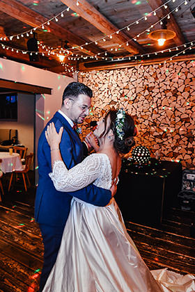 Hochzeitstanz unter Lichterketten im rustikalen Saal